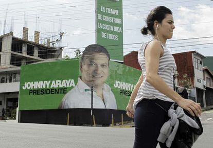 Una mujer camina frente a propaganda del candidato oficialista 