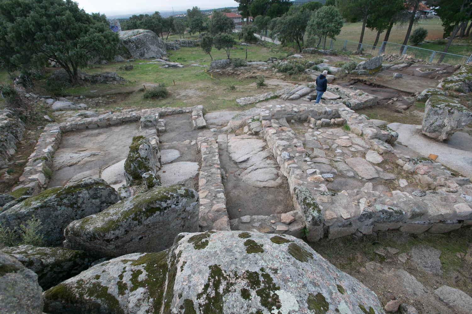 Muros del complejo religioso del yacimiento de Hoyo de Manzanares y, al fondo, los restos de las viviendas que se extienden ladera abajo.