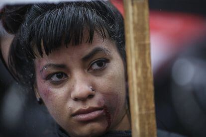 Una mujer con maquillaje alusivo a los golpes que reciben las mujeres víctimas de violencia, asiste a la marcha contra la violencia machista.