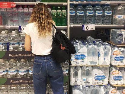 Una joven frente al estante de botellas de agua de plástico en un supermercado en Madrid.
