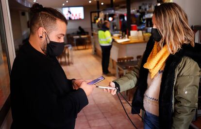 Un camarero solicita el pasaporte covid a un cliente en un restaurante de Terrassa.