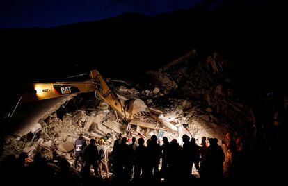 Los equipos de rescate trabajan de noche frente a una casa derruida, en Pescara del Tronto.