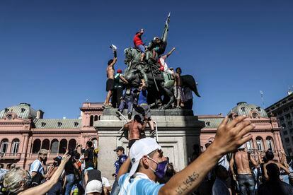 La Plaza de Mayo, frente a la Casa Rosada, ha sido escenario de todos los acontecimientos políticos y sociales más significativos de Argentina. El 26 de noviembre de 2020, decenas de miles de personas se reunieron para despedir a Diego Maradona en la capilla ardiente montada en la sede del Gobierno. En la foto, un grupo de hinchas sube la estatua ecuestre que recuerda a José de San Martín.