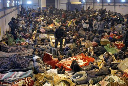 Una multitud de refugiados huidos de Libia descansa en un pabellón industrial cercano al paso fronterizo de Ras el Ajdir, en Túnez.