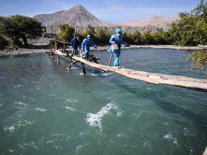 Trabajadores de salud cruzan el río Camaná para vacunar a ancianos contra COVID-19, en Arequipa, sur de Perú.