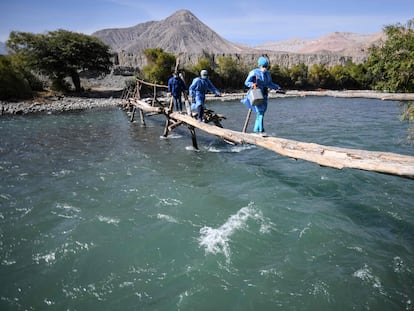 Trabajadores de salud cruzan el río Camaná para vacunar a ancianos contra COVID-19, en Arequipa, sur de Perú.