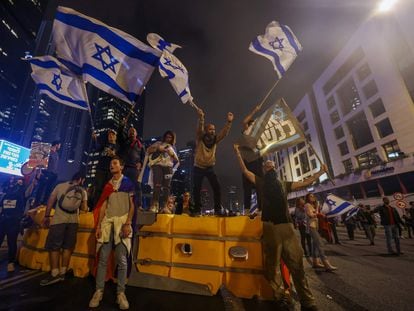 Manifestantes israelíes ondean banderas nacionales encaramados en una barricada, durante la protesta contra el proyecto de reforma judicial, este sábado en Tel Aviv.