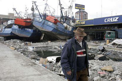 Un superviviente del terremoto camina cerca de varios barcos que acabaron en tierra firme por el impulso del maremoto en Talcahuano.
