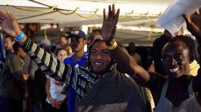 Varios migrantes agitan los brazos antes de desembarcar del Open Arms en Lampedusa.