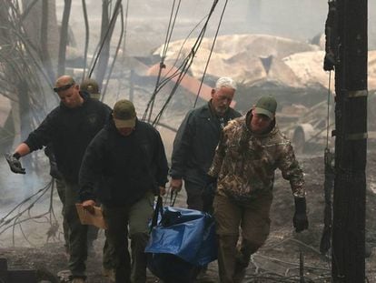 Agentes de policía retiran un cadáver recuperado de los escombros en Paradise, California. En vídeo, más de 30 fallecidos y 100 desaparecidos en el incendio que afecta a California.