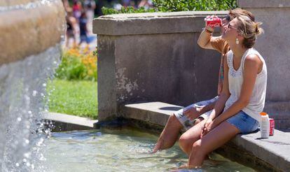 Dos jóvenes se refrescan en la plaza de Catalunya de Barcelona.