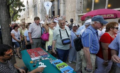 Un grupo de cruceristas pasa frente a un puesto de numismática tras visitar la Lonja de Valencia.