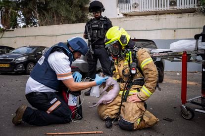 Un bombero y un paramédico atienden a un gato herido de un edificio alcanzado en Tel Aviv por un cohete lanzado desde Gaza, este viernes. 