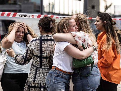 People hug each other outside the Fields shopping mall, where a gunman killed three people and wounded several others in Copenhagen on July 3, 2022. - A 22-year-old Danish man was arrested after the shooting but his motives were unclear, police said. (Photo by Olafur STEINAR GESTSSON / Ritzau Scanpix / AFP) / Denmark OUT