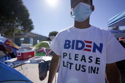 Un hondureño que busca asilo en Estados Unidos usa una camiseta que dice “Biden, por favor déjenos entrar”, mientras se para entre las tiendas de campaña en la línea de entrada al cruce fronterizo este martes, en Tijuana.