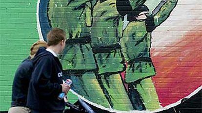 Una familia pasa delante de un mural del IRA en Belfast, en julio de 2002.