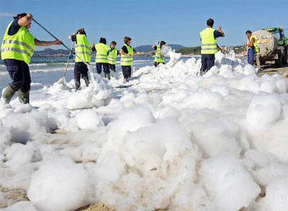 Operarios municipales y de Tragsa retiran la espuma depositada en el arenal de Samil.