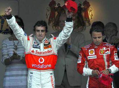 Fernando Alonso levanta sus brazos junto a un cariacontecido Felipe Massa.