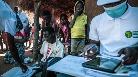 Rodeado por su mujer e hijos, Balança Manuel Sande rellena unos impresos que le han entregado los encuestadores del Centro de Investigación de Salud de Manhiça (CISM), en Mozambique, que colaboran con el Proyecto Bohemia.