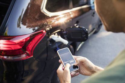 Un automovilista usa su móvil mientras espera que cargue la batería de su vehículo eléctrico.