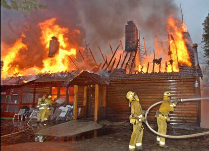 Cuatro bomberos tratan de extinguir el fuego en una casa de Lake Arrowhead en octubre de 2003.