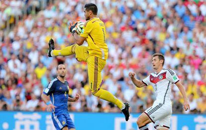 El guardameta argentino Sergio Romero para el balón ante el delantero alemán Miroslav Klose.
