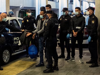 Dos jóvenes migrantes marroquíes esposados llegan al aeropuerto de Las Palmas, Canarias para ser deportados por la policía, en diciembre 2020.