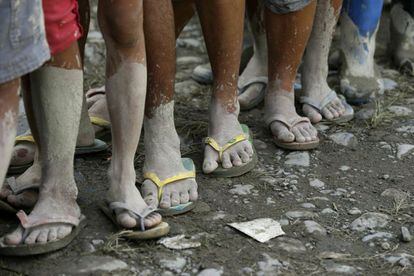 Varios de los evacuados por el tif&oacute;n hacen cola para obtener comida en un campamento para refugiados.