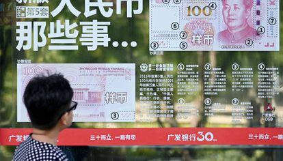 Una mujer mira un anuncio con los nuevos billetes del yuan, en Pekín.
