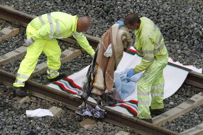 Operarios retiran de la vías mantas y otros enseres que permanecían en el lugar del accidente de tren ocurrido anoche en Santiago de Compostela, 25 de julio 2013.