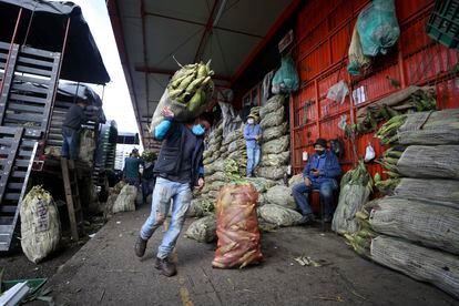 Un hombre con mascarilla lleva un saco de maíz en Corabastos, uno de los centros de distribución de alimentos más grandes de América Latina en Bogotá, Colombia, el martes 23 de junio de 2020.