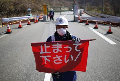 Un guarda de seguridad sostiene una bandera que dice "¡Pare!" en un puesto de control de Fukushima.