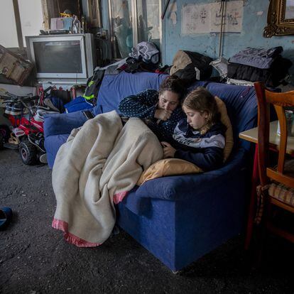 A woman rests with her daughter inside their home at the Canada Real shanty town, outside Madrid, Spain, Tuesday, Jan. 12, 2021.  Shops are flimsy set-ups with little stock and the residents live off construction jobs, scrap metal collection or whatever they can, and the area has long been associated with drugs. (AP Photo/Manu Fernandez)