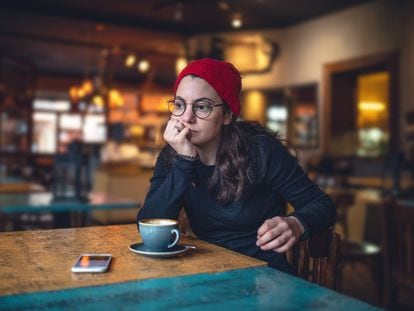 Una mujer con la mirada perdida en una cafetería, quizás se ha cruzado con más 'beige flags' de las que puede gestionar.