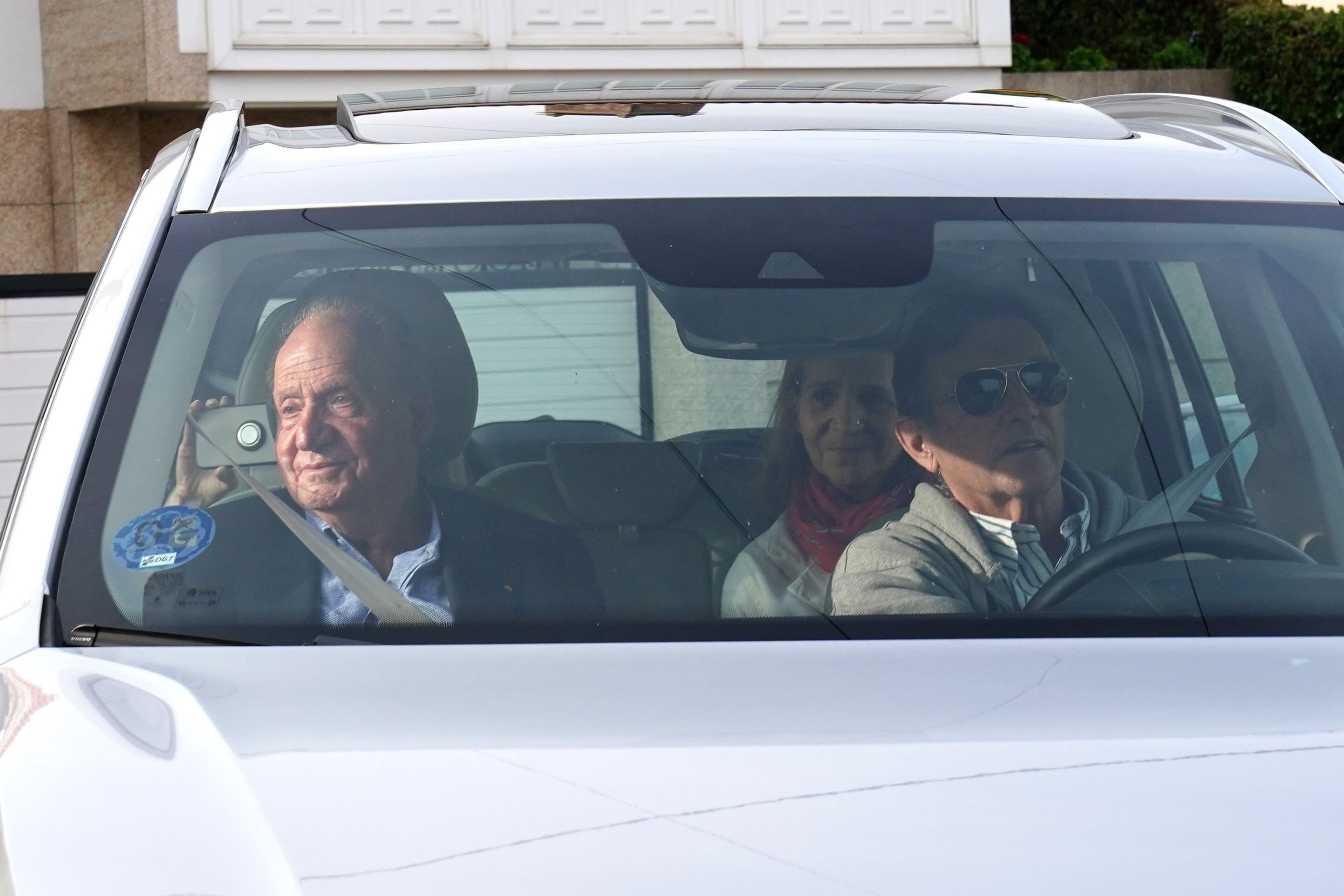El rey Juan Carlos I (a la izquierda) saluda a su llegada a la vivienda de su anfitrión, Pedro Campos (a la derecha, al volante) en Sanxenxo (Pontevedra), este jueves. En el asiento de atrás, a la derecha, la infanta Elena.