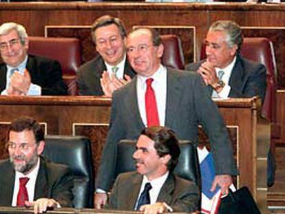 Rato, de pie tras Aznar y Rajoy, recibe los aplausos de su grupo parlamentario durante la sesión de control al Ejecutivo en el Congreso.