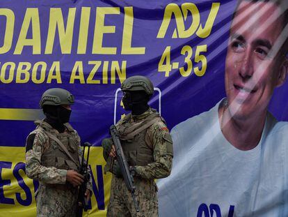 Soldados se encuentran frente a una pancarta que muestra al candidato presidencial ecuatoriano Daniel Noboa.