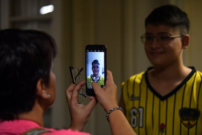 A woman takes a picture of her son wearing his new pair of glasses.