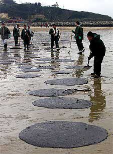 Equipos de limpieza, en la playa de Merón, en San Vicente de la Barquera.