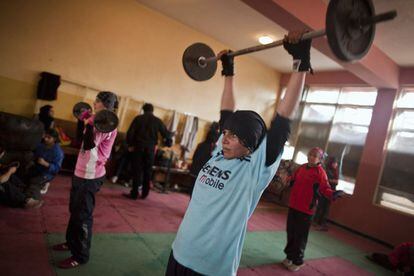 Shabnam Rahimi, 19 años y camiseta azul, y su hermana Sadaf, con la camiseta rosa, levantan pesas en el gimnasio.