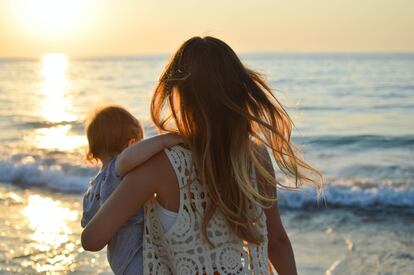Una madre abraza a su hijo frente al mar.