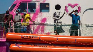 A boy waves to the crew of the Astral rescue vessel from the deck of the Louise MichelÂ rescue vessel, a French patrol boat currently manned by activists and funded by the renowned artist Banksy in the Central Mediterranean sea, at 50 miles south from Lampedusa, Friday, Aug. 28, 2020. A Berlin-based group says it has begun migrant rescue operations in the Mediterranean Sea with a bright pink former navy vessel sponsored by British artist Banksy. The group operating the MV Louise Michel, a sleek 30-meter (98-foot) ship named after a 19th century French feminist and anarchist, said late Thursday that it rescued 89 from an inflatable boat in distress. (AP Photo/Santi Palacios)