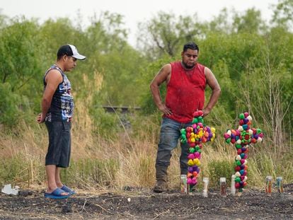 Dos hombres bajo la lluvia contemplan el memorial improvisado cerca del sitio donde fue encontrado el camión de remolque con los migrantes hacinados, el 28 de junio, en San Antonio, Texas, (EEUU).