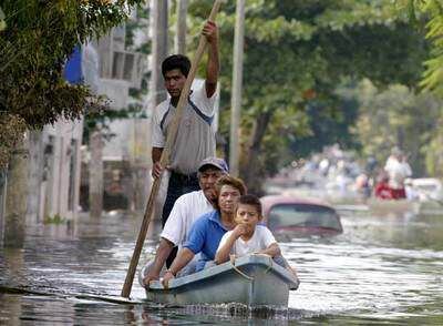 Los miembros de una familia van en una pequeña barca por una calle de Villahermosa, la capital inundada del Estado de Tabasco.
