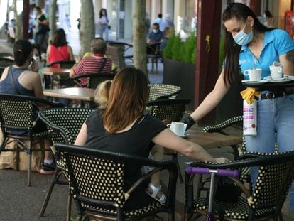 Una camarera sirve en una terraza de un bar de Sabadell.