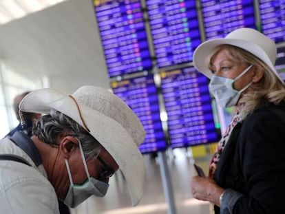 Dos viajeros con mascarillas esperan su vuelo en el aeropuerto de El Prat. 
