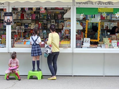 Dos ni&ntilde;as hojean libros en la Feria del Libro de Madrid.