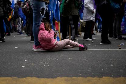 Una niña usa el móvil mientras descansa a los pies de su madre, durante la protesta.