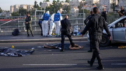 Un policía apunta a uno de los supuestos atacantes del tiroteo en Jerusalén, mientras los sanitarios atienden a los heridos.