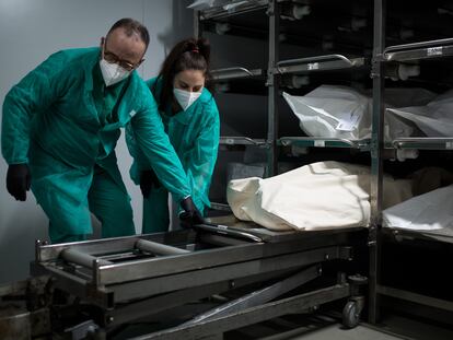 Dos empleados preparan el cuerpo de un fallecido para introducirlo en un ataúd, en el tanatorio Sancho de Ávila, en Barcelona.